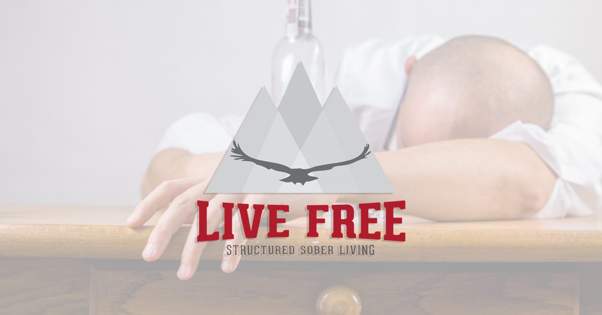 Man laying on a desk with bottle next to home. Live Free Logo overtop