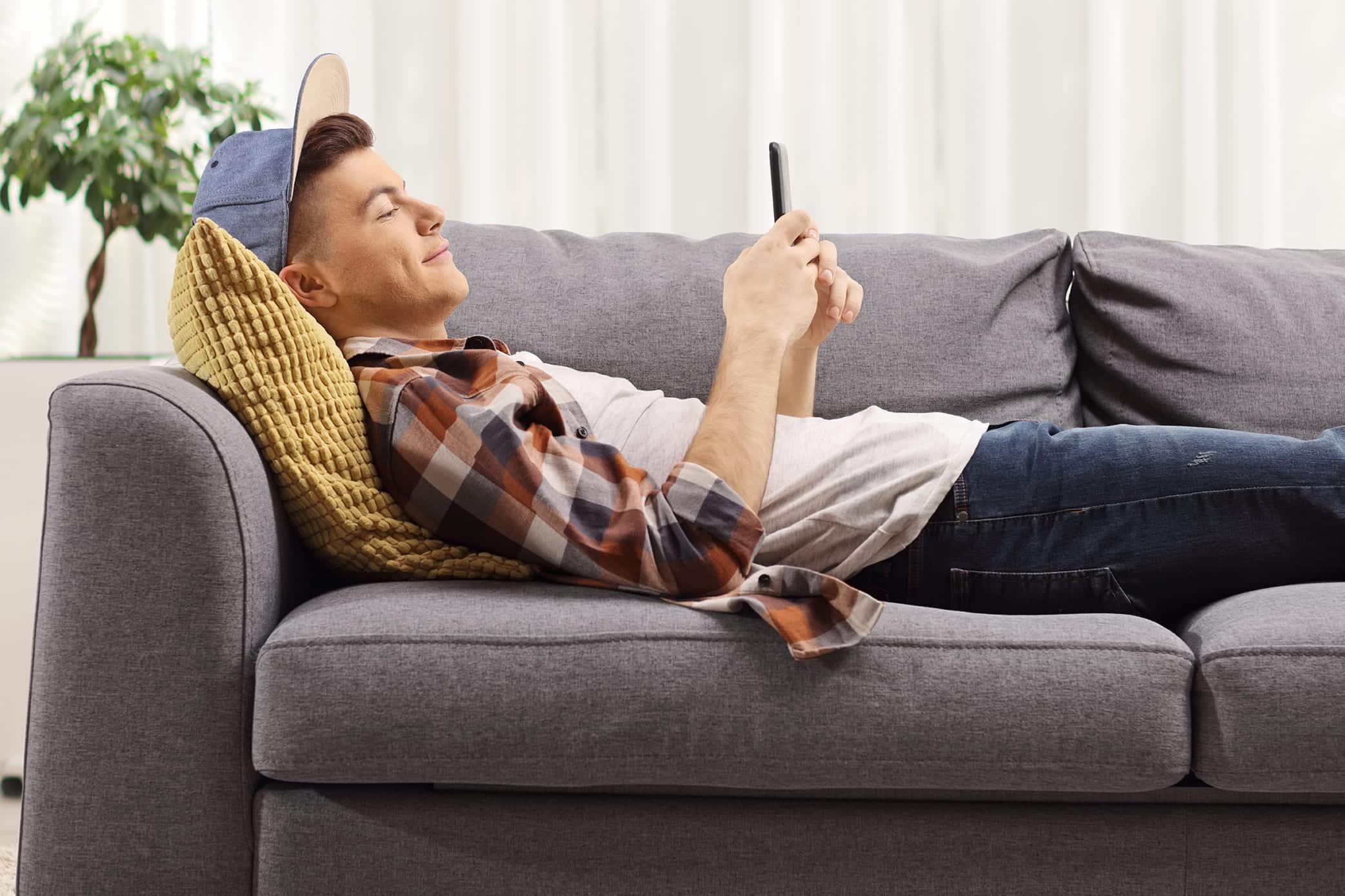 man relaxing on couch looking at phone